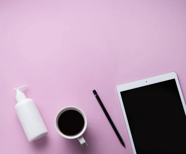 Home work. Business flat lay with cup of coffee, sanitizer and tablet  on pink background. Image top view, flat lay and copy space