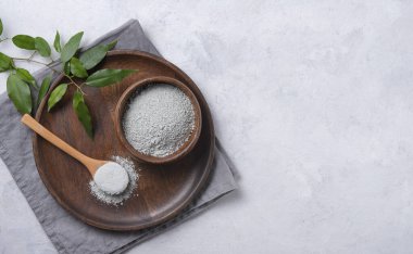 Kozmetik yeşil kilden yapılmış maske gri beton arka planda bir ahşap kasede. Üst görünüm, düz görünüm ve boşluk kopyala.