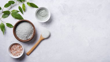 Evdeki ahşap bir kasede kozmetik yeşil kil ve gri beton arka planda pembe deniz tuzu maskesi. Kendi kozmetolojistim. Üst görünüm, düz görünüm ve boşluk kopyala.