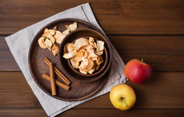 sweet homemade Apple chips dried with cinnamon in wood bowl on wooden background. Vegan and dietary product. Top view and copy space