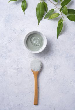 Evdeki kozmetik kilden yapılmış maske gri beton arka planda küçük bir kasede. Üst görünüm, düz görünüm ve boşluk kopyala.