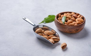 Tahta bir kasede bademler ve mavi arka planda bir kepçe. Boşluğu kopyala