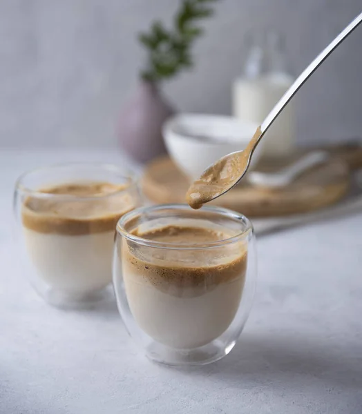 ビーガンミルクとスプーンを背景にしたガラスカップの中のアロマダルゴナコーヒー トレンディ ドリンク マクロビュー — ストック写真