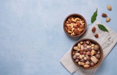 Mavi arka planda gri peçetede iki ahşap kasede fındık karışımı. Vejetaryen ürünü. Üst görünüm ve kopyalama alanı