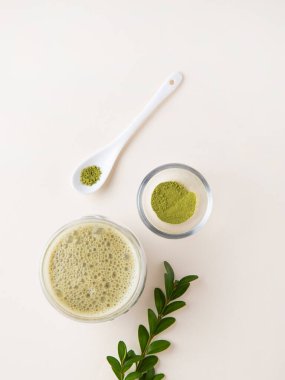  Açık bir bardakta, sarı arka planda çiçekler ve kaşıkla kibrit çayı. Moda vejetaryen içeceği. Üst görünüm ve kopyalama alanı