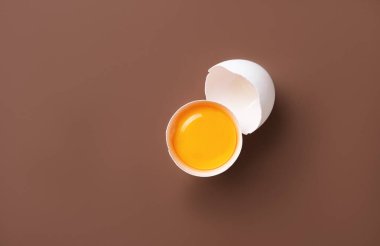 Kahverengi arka planda iki parçaya ayrılmış taze bir yumurta. Üst görünüm ve boşluk kopyala. Resmi kavra