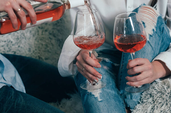 A man in jeans fills glasses with rose wine
