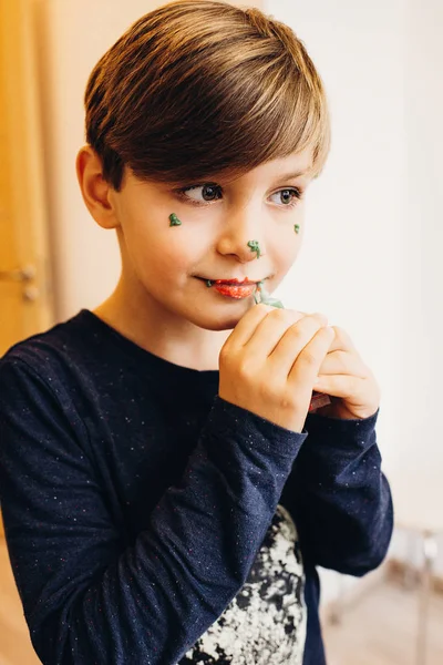 Ładny chłopak maluje jego twarz z jadalnych kolor krem — Zdjęcie stockowe