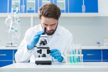 Biyolojik araştırma. Akıllı güzel kendinden emin bilim adamı mikroskop içine bakarak ve biyolojik araştırma yaparken örnekleri test