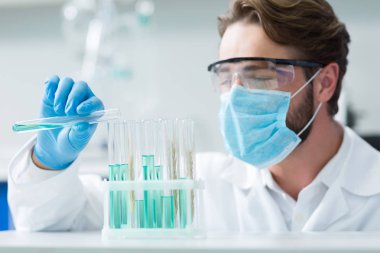 Organik kimya. Güzel akıllı erkek kimyager tarafından bakılıyor ise kabukları üzerinde duran test tüpleri seçici odak