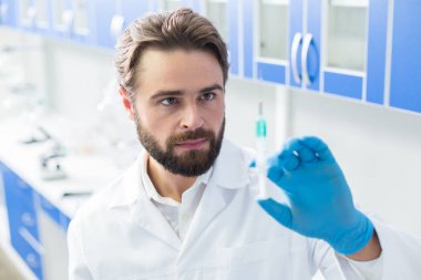 Hastane laboratuarı. Akıllı güzel erkek bilim adamı bir şırınga holing ve hastane laboratuvarında çalışırken ona bakarak