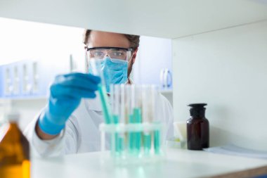 Tıbbi araştırma. Akıllı güzel profesyonel bilim adamı test tüpleri bakarak ve tıbbi laboratuvarda çalışırken analiz için alarak