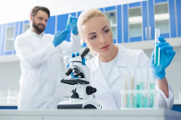 Mujer agradable agradable sosteniendo un tubo de ensayo — Foto de Stock