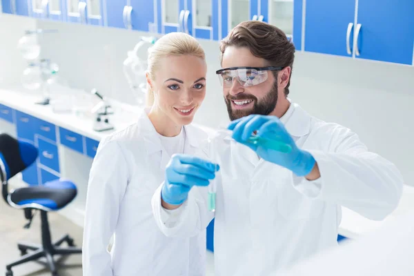 Bons cientistas felizes olhando para os tubos de ensaio — Fotografia de Stock