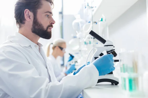 Serious smart biologist setting up the microscope — Stock Photo, Image