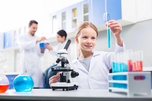 Agradable chica alegre examinando líquido en el vial — Foto de Stock