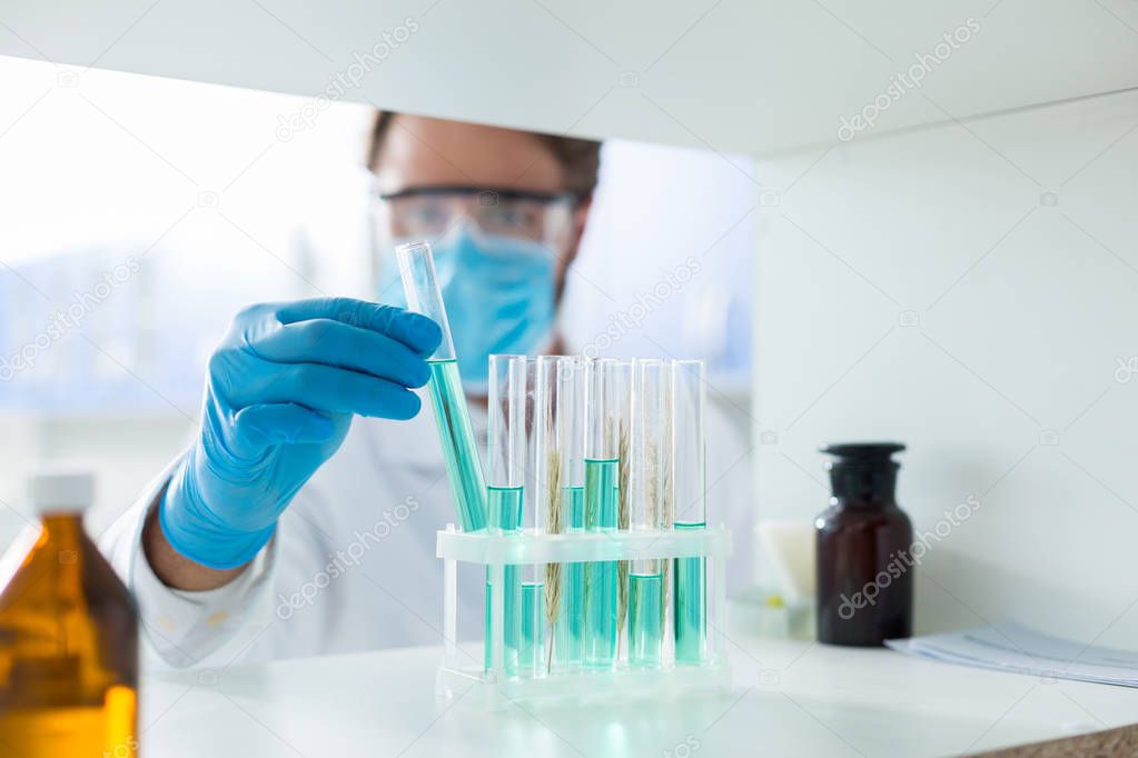 Laboratory test sample. Selective focus of test tube with blue liquid being taken out from the test tube rack