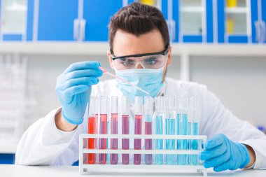 Bir damla. Onlar ayakta iken şişeler sıvı koymak için pipet kullanarak odaklanmış yetenekli erkek laboratorian
