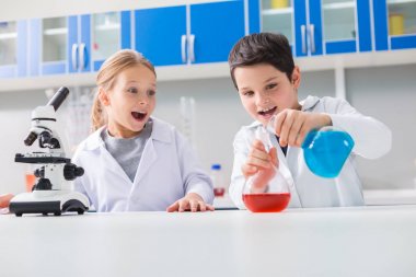 İlginç bir kimya. Pozitif neşeli akıllı çocuk laboratuvarda iken şişeleri tutan ve kimyasal reaktifler karıştırma