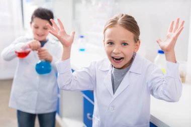 Ne yapmalı? Pozitif duygusal sevimli kız size bakıyor ve ne yapacağını bilmeden ellerini yukarı tutarak