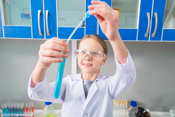 Funny science. Cute jolly gay girl working with liquid while posing at lab and grinning