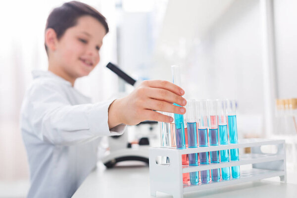 Best worker. Selective focus of vials filled with liquid while boys hand stretching to them