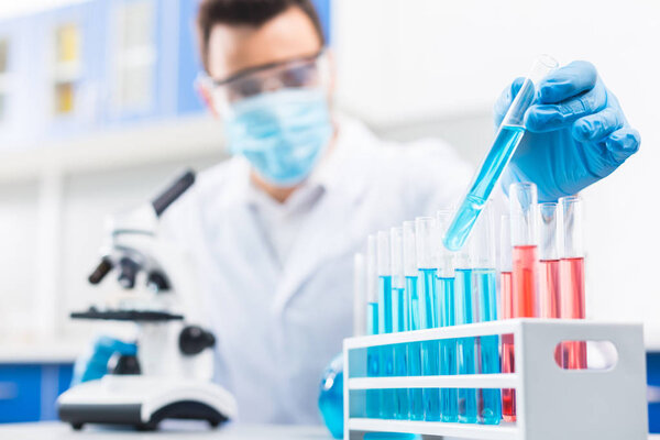 Blue reagent. Selective focus of glass vial poured with reagent and using for research which hold male hand