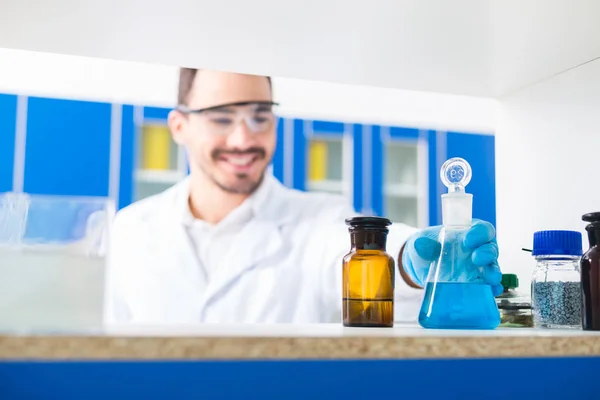 实验室里面男性手拿实验室眼镜的选择性焦点 其中液体倒入并站在表面上 — 图库照片