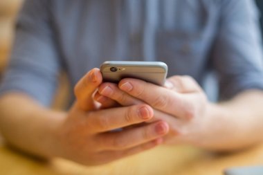 Modern bir alet. Modern bir akıllı telefon seçici odak kullanırken güzel yakışıklı genç bir adamın elinde olmak