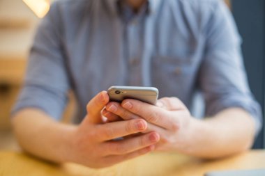 Dijital teknoloji. Modern akıllı telefon masada otururken olumlu bir güzel adam tarafından kullanılmakta olan