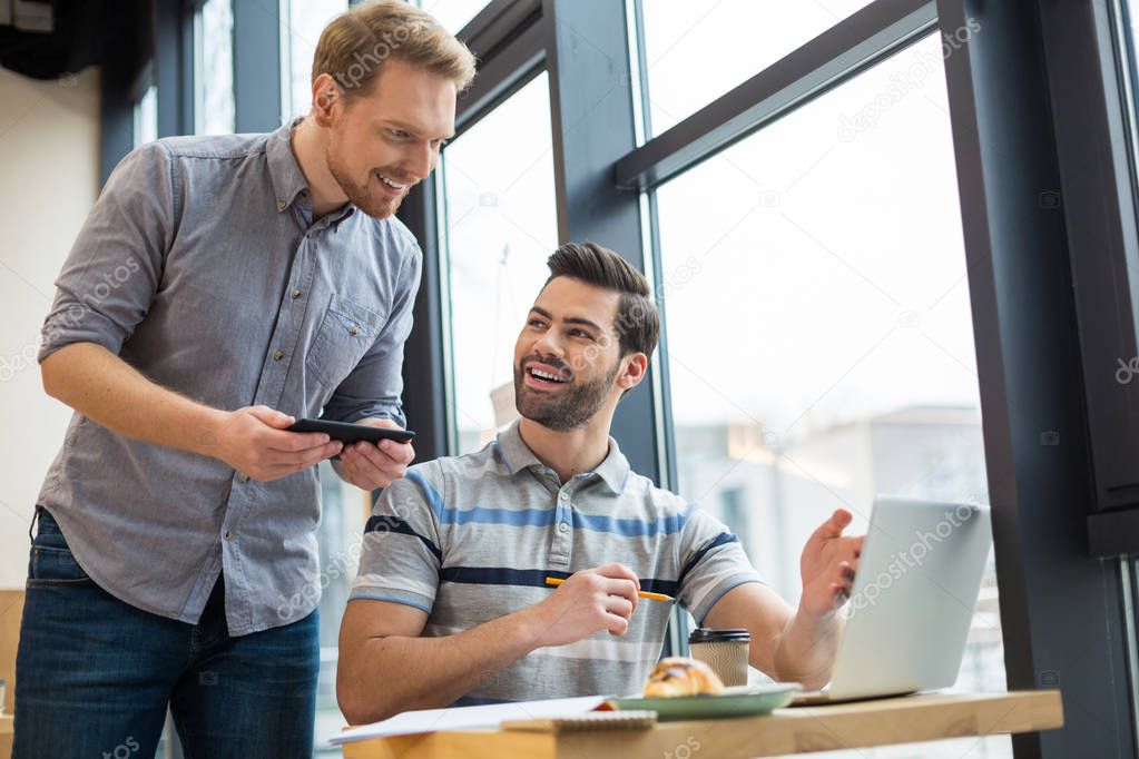 New ideas. Nice pleasant smart men smiling and talking to each other while discussing their idea