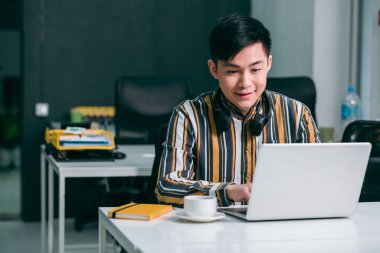 Kendine güvenen bir ofis çalışanı masada oturuyor ve bir dizüstü bilgisayar üzerinde çalışıyor.