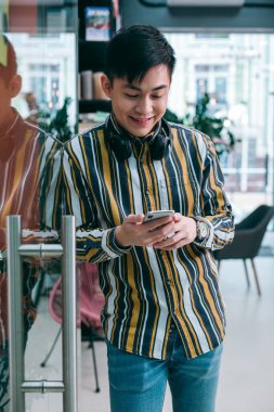 Ofisteki cam kapının yanındaki genç adam gülümseyen bir akıllı telefonun ekranına bakıyor.