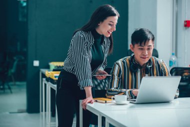 Gülümseyen meslektaşlar dizüstü bilgisayara bakıyorlar ve yaptıkları işten gurur duyuyorlar.