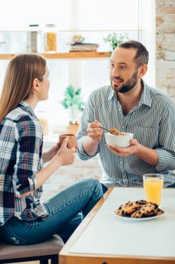 Gevrek yerken güzel bir bayanla konuşan sakin bir adam.