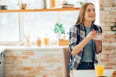 Neşeli genç bir bayan başka tarafa bakıyor ve kaseden mısır gevreği yiyor. Şablon pankartı