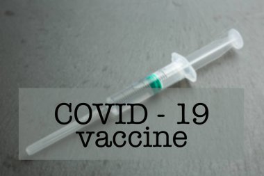 COVID-19 aşı yazıları. Arka planda şırınganın bulanık fotoğrafı