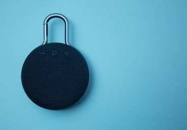 Mavi arka planda izole edilmiş küçük siyah taşınabilir hoparlör düzlüğü. Web sitesi afişi