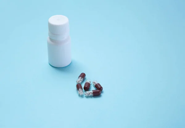 Μικρό Λευκό Μπουκάλι Χάπια Μπλε Φόντο Και Πέντε Ιατρικές Κάψουλες — Φωτογραφία Αρχείου