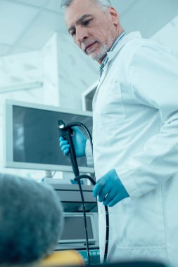 Modern bir endoskopla yanında duran sakin, olgun bir doktor.