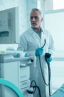 Sakin ol, olgun doktor. Ekrana bakıp elinde endoskop resmi tutuyor.