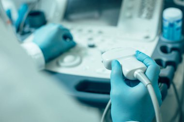 Plastik eldivenli bir sağlık çalışanının ultrason teşhis ekipmanını kullanırken çekilmiş fotoğrafı.