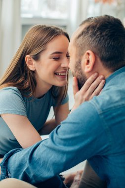 Pozitif genç bayan erkek arkadaşına doğru eğiliyor ve gözlerini kapatırken onun yüzüne dokunuyor.