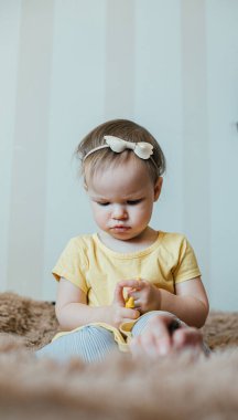 Saçında bantla yatakta tek başına otururken parmağına dokunan güzel bir kız.