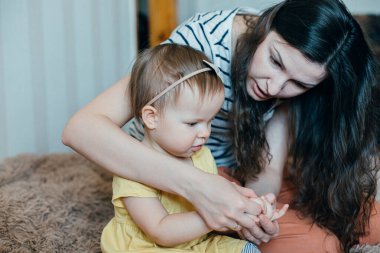 Küçük tatlı bir kız parmaklarına bakıyor ve sakin bir anne onunla birlikte sayıyor.
