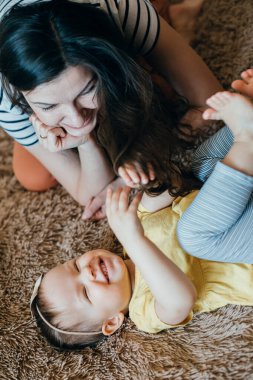 Yumuşak bir battaniyeye uzanmış, annesinin uzun saçlarına dokunarak gülüyordu.