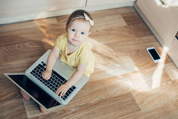 漂亮的一岁小女孩 带着笔记本电脑坐在地板上 面带微笑 — 图库照片