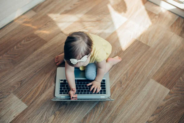 一位可爱的小女孩坐在家里的地板上 触摸着现代笔记本电脑的屏幕和键盘 — 图库照片