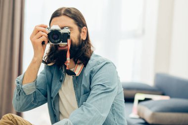 Kot gömlekli memnun adam senin fotoğraflarını çekerken mutlu bir şekilde gülümsüyor.