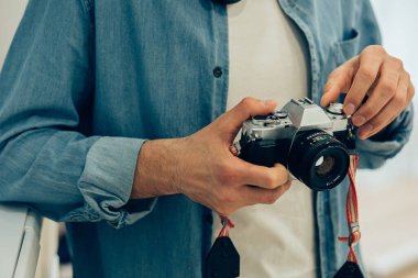 Elinde şık bir fotoğraf makinesi olan sıradan giyinmiş birini yakından çek.